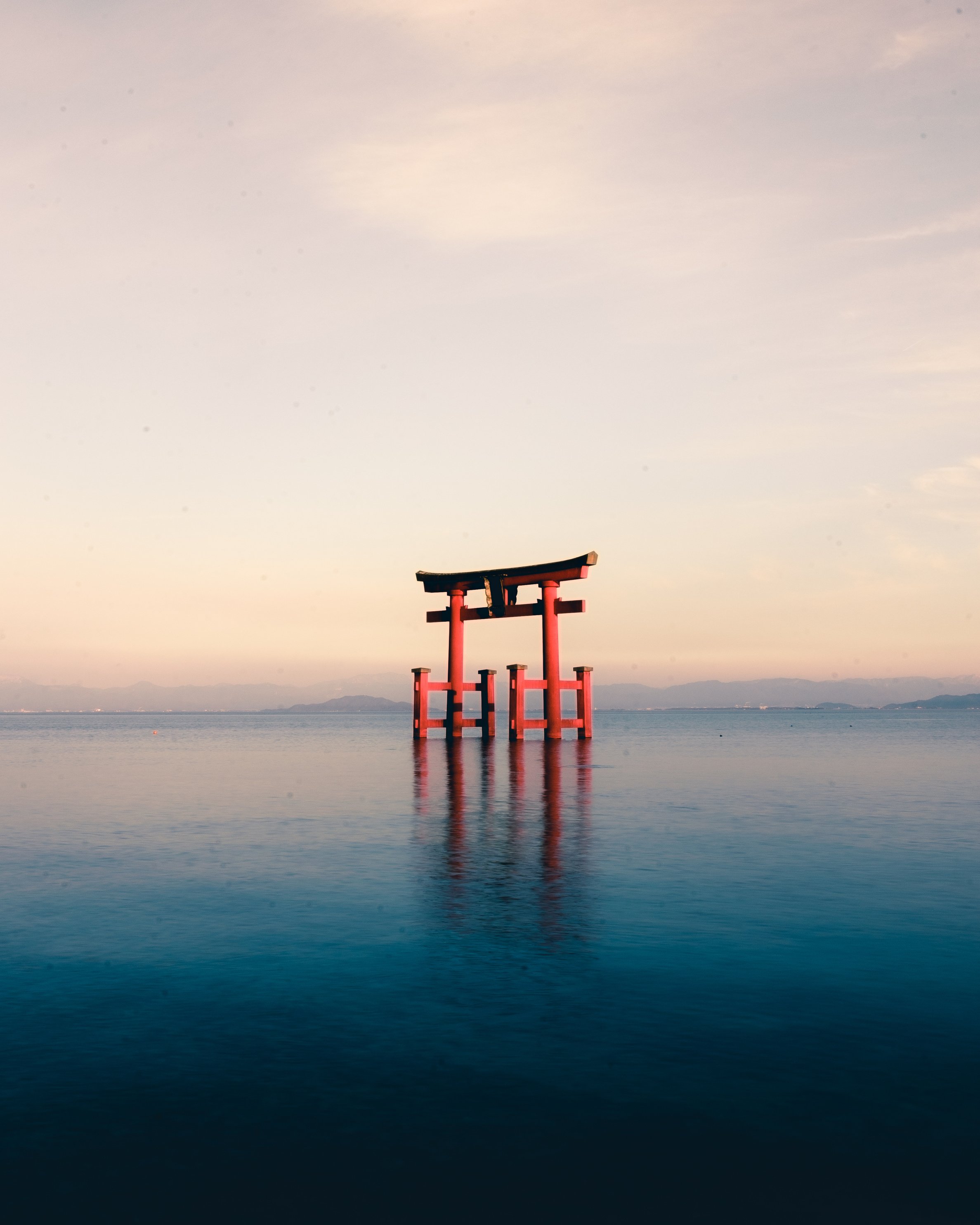 Orange wooden gate on body of water under white sky